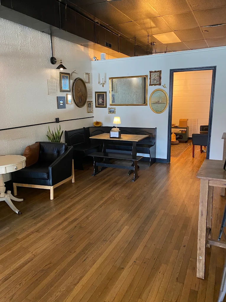 A corner with a black bench nook and table, a leather armchair, and a wall of framed pictures.